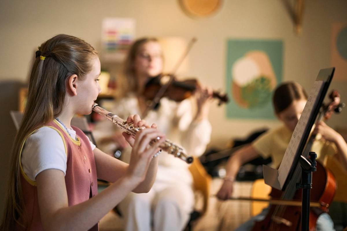 Kids studying music and playing flute, violin, and cello during lesson, developing creativity and teamwork